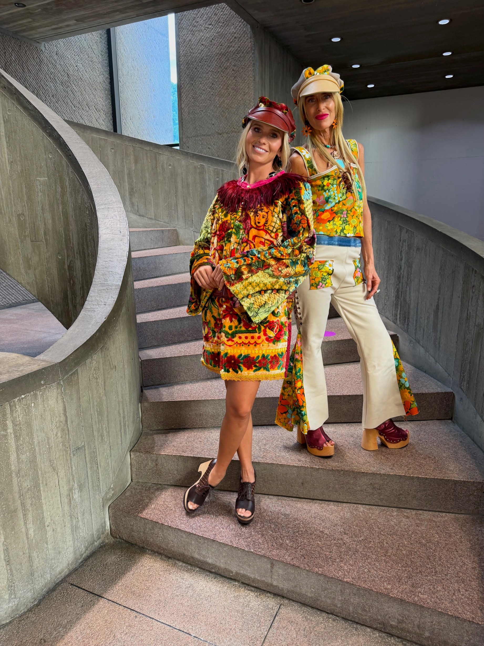 Michelle DaRin and friend in bold colorful looks on a museum staircase