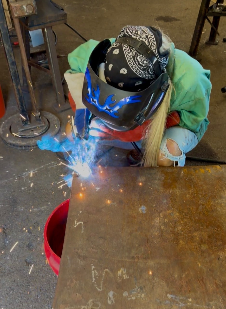 Michelle DaRin welding in the studio with sparks flying